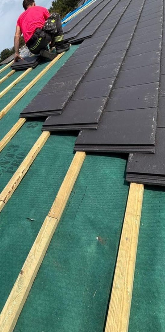 Roofer fitting new tiles course by course